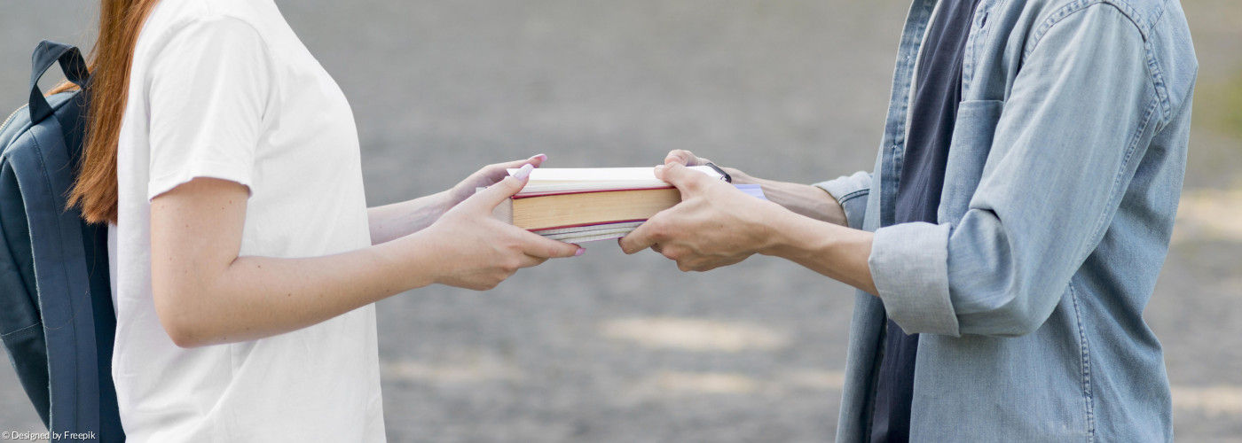 Zwei Menschen geben sich ein Buch in die Hand