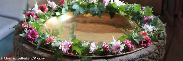 Taufstein mit Blumenkranz