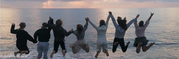 Jugendliche, die sich an den Händen halten und am Strand in die Luft springen