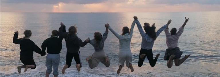 Jugendliche, die sich an den Händen halten und am Strand in die Luft springen